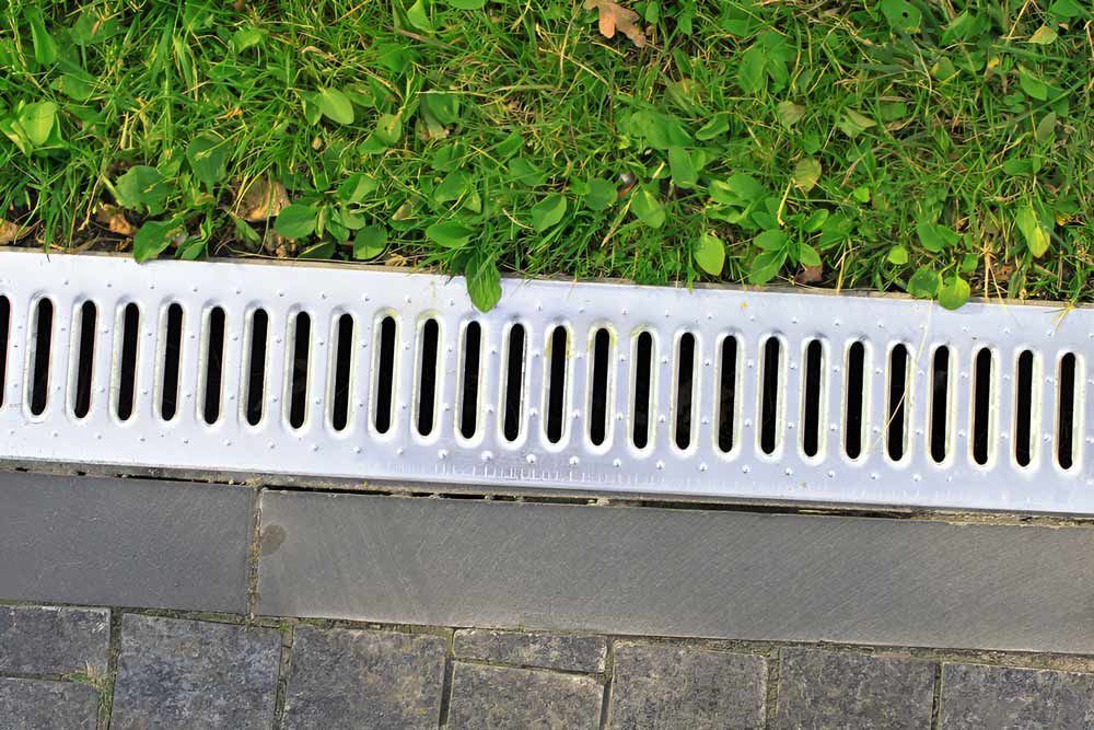 Drainage System Separates The Grass And The Paved Sidewalk — Austen Landscaping & Earthmoving in Deeragun, QLD