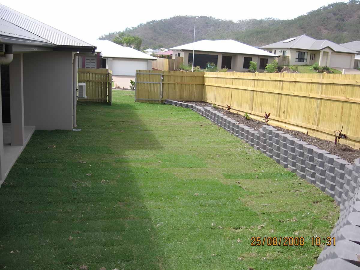 Landscape backyard with a wooden fence And Brick Retaining Wall — Austen Landscaping & Earthmoving in Wulguru, QLD