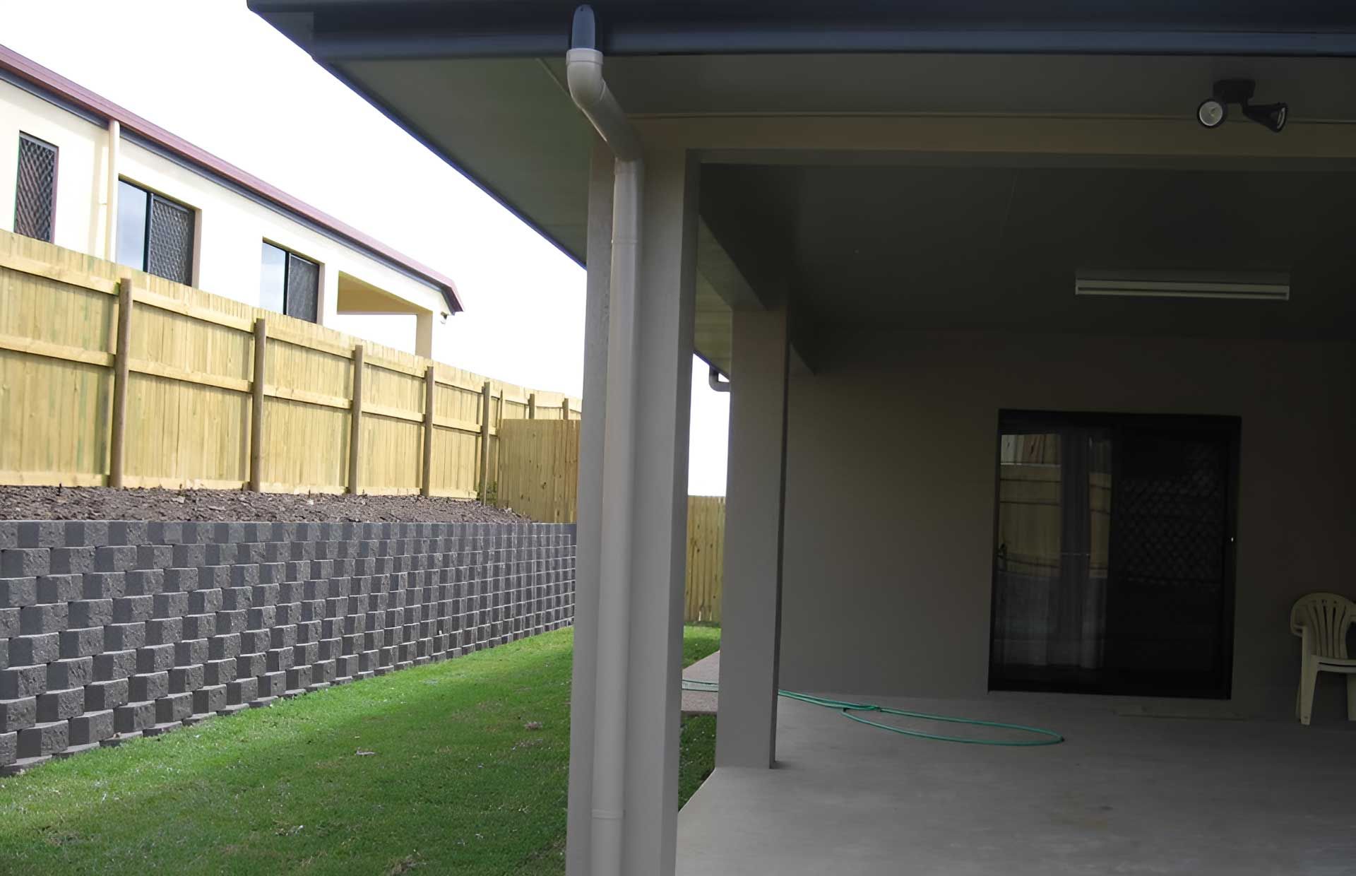 A House Backyard With A Fence And Patio And Garden Retaining Wall — Austen Landscaping & Earthmoving in Deeragun, QLD