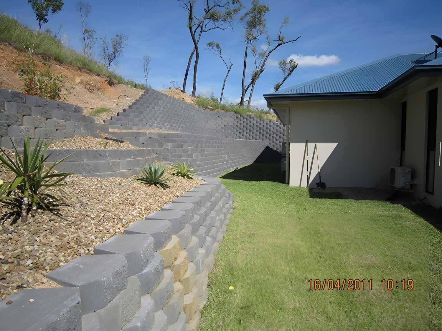 A House With A Brick Retaining Wall And A Fence — Austen Landscaping & Earthmoving in Deeragun, QLD