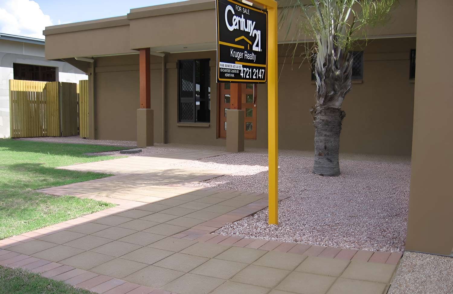 A Century 21 Sign Hangs Outside Of A House With Pavement — Austen Landscaping & Earthmoving in Deeragun, QLD