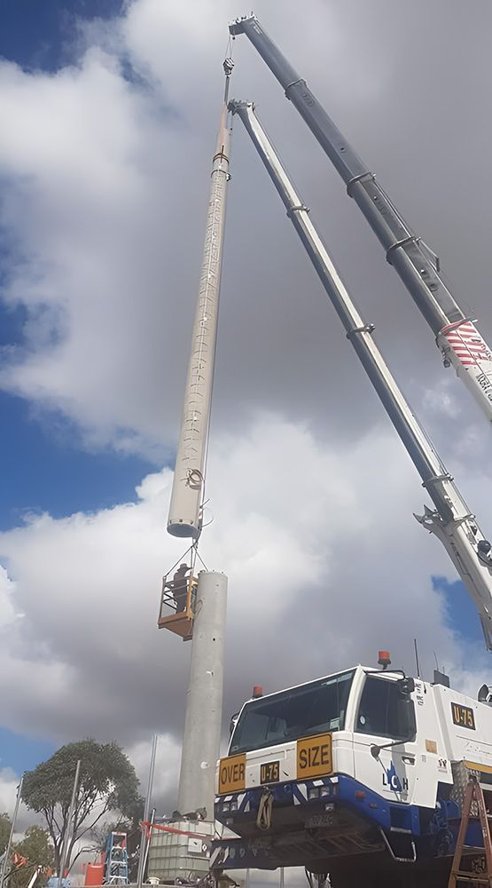 A Crane Is Lifting A Concrete Pole Into The Air — Austen Landscaping & Earthmoving in Bushland Beach, QLD