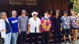 Group of people standing outside a building, posing for a photo, some in colorful casual clothing.