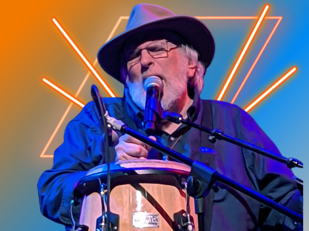 Singer in a cowboy hat performing into a microphone on stage with blue and orange lights.