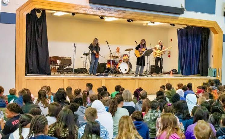 School band performs onstage for a seated audience in a gymnasium