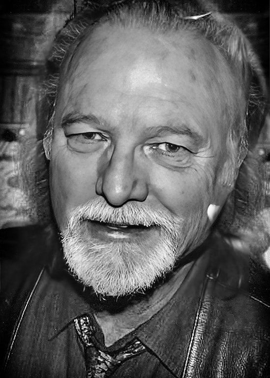 Black-and-white close-up portrait of a smiling man with a beard and leather jacket