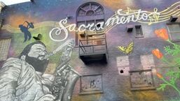 Mural with the word “Sacramento,” a black-and-white figure, and colorful birds on a building wall