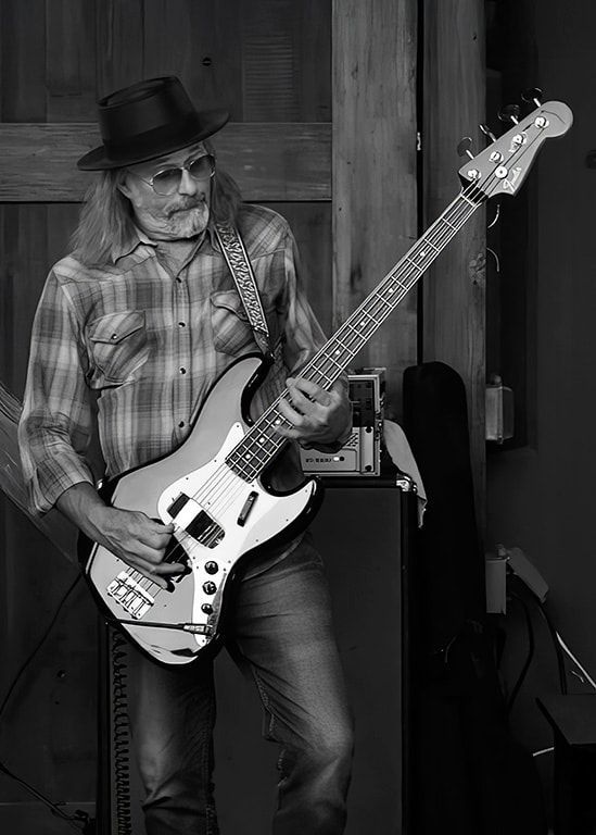 Man in a hat playing an electric guitar in a rustic indoor setting