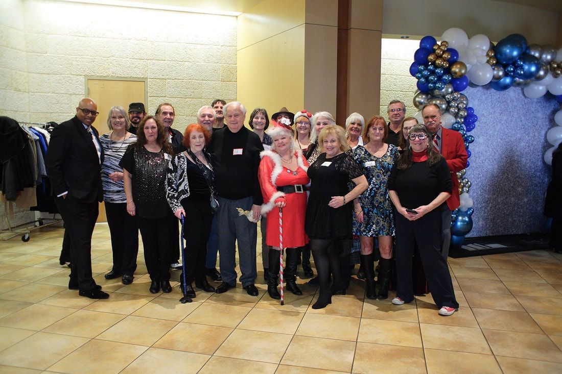 Group of people posing at an indoor event with blue and gold balloon decorations