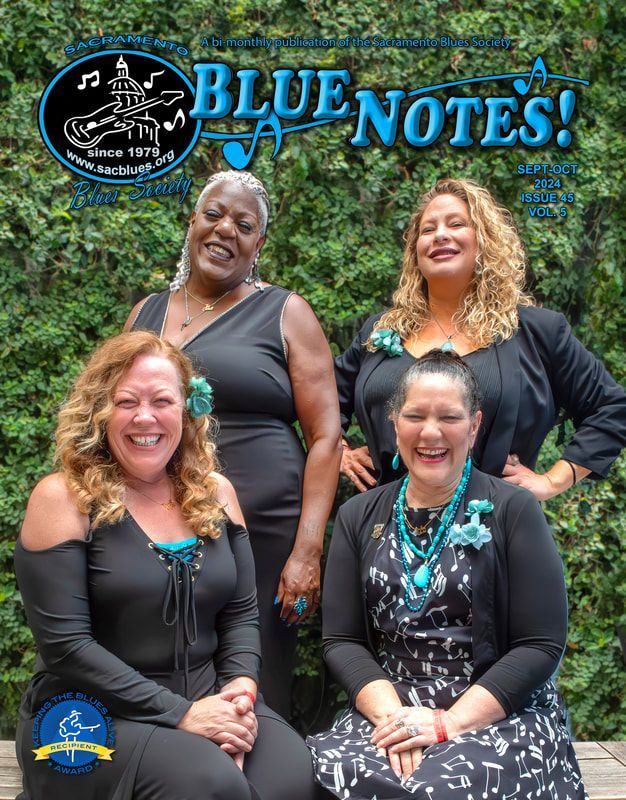 Four smiling people pose outdoors beneath a “BLUE NOTES!” logo and sign.