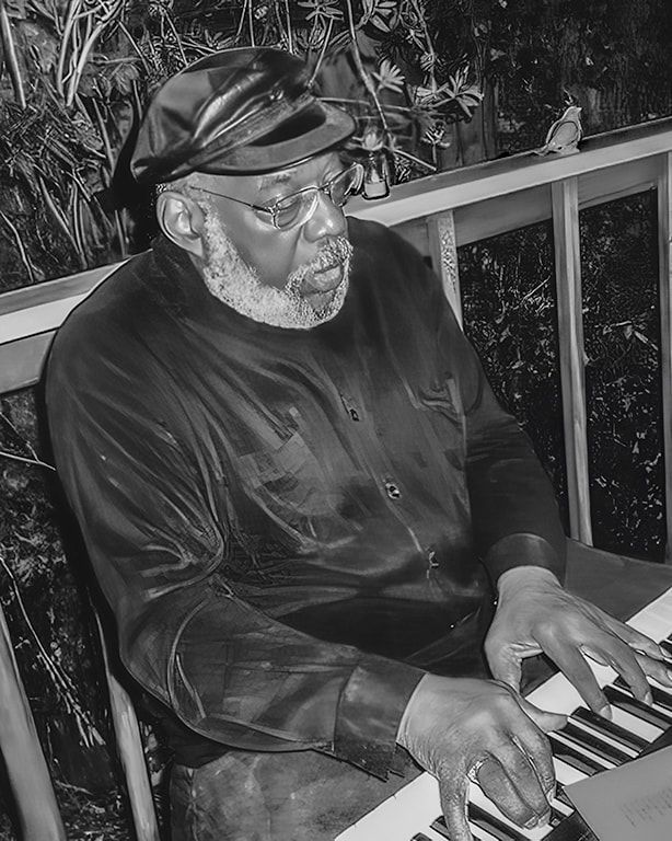 Black-and-white photo of a man in a cap playing a keyboard on a porch at night