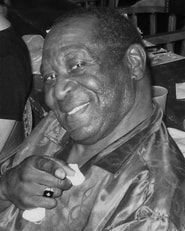 Smiling man in a shiny jacket holding a small object near his face