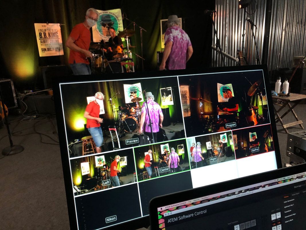 Camera monitor showing two performers on stage, with colorful lighting and multiple preview thumbnails