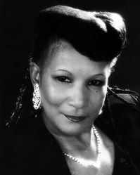 Black-and-white portrait of a woman with an updo, earrings, and a slight smile