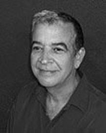 Black-and-white portrait of a smiling man against a dark background