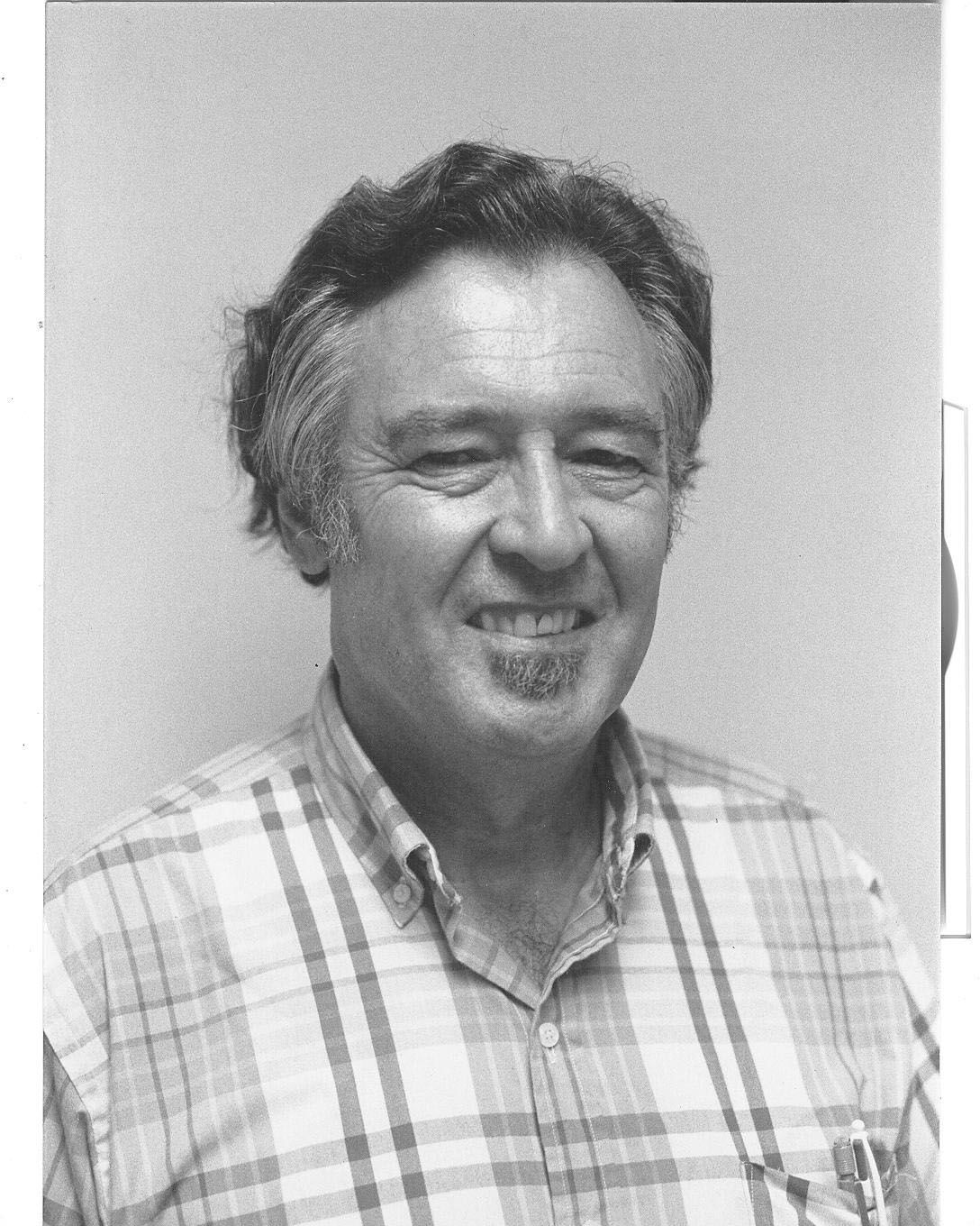 Smiling man in a plaid shirt against a plain background