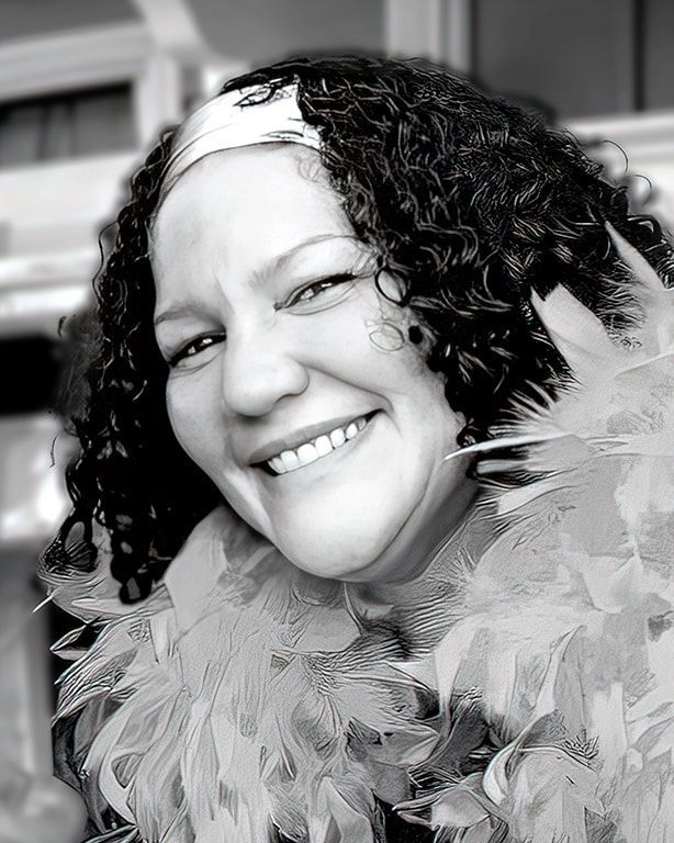 Smiling person with curly hair wearing a feathery collar, in black and white.