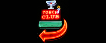 Neon Torch Club sign with red arrow and blue martini glass on black background
