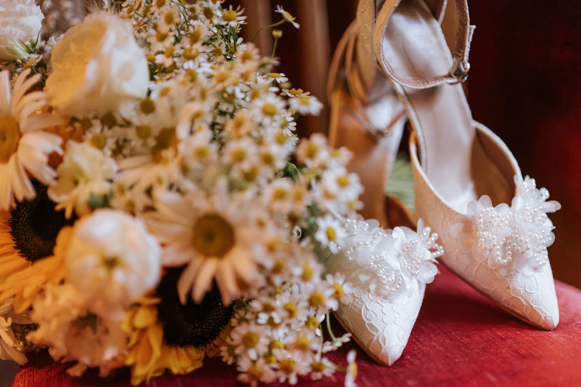 Rustic indoor wedding reception aisle with wooden chairs, white drapes, and greenery overhead