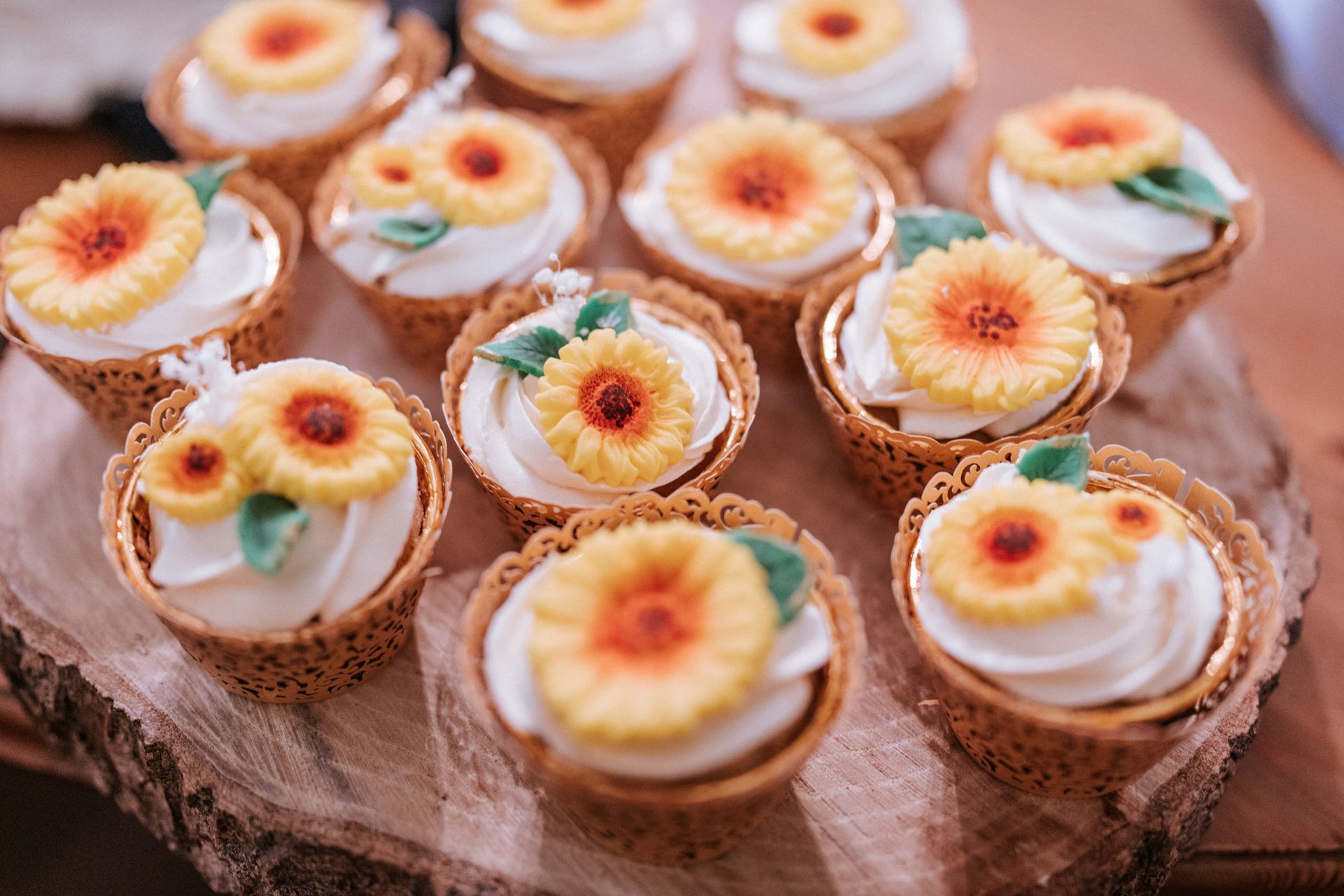 Assorted mini fruit tarts topped with whipped cream and flowers on a rustic wooden board