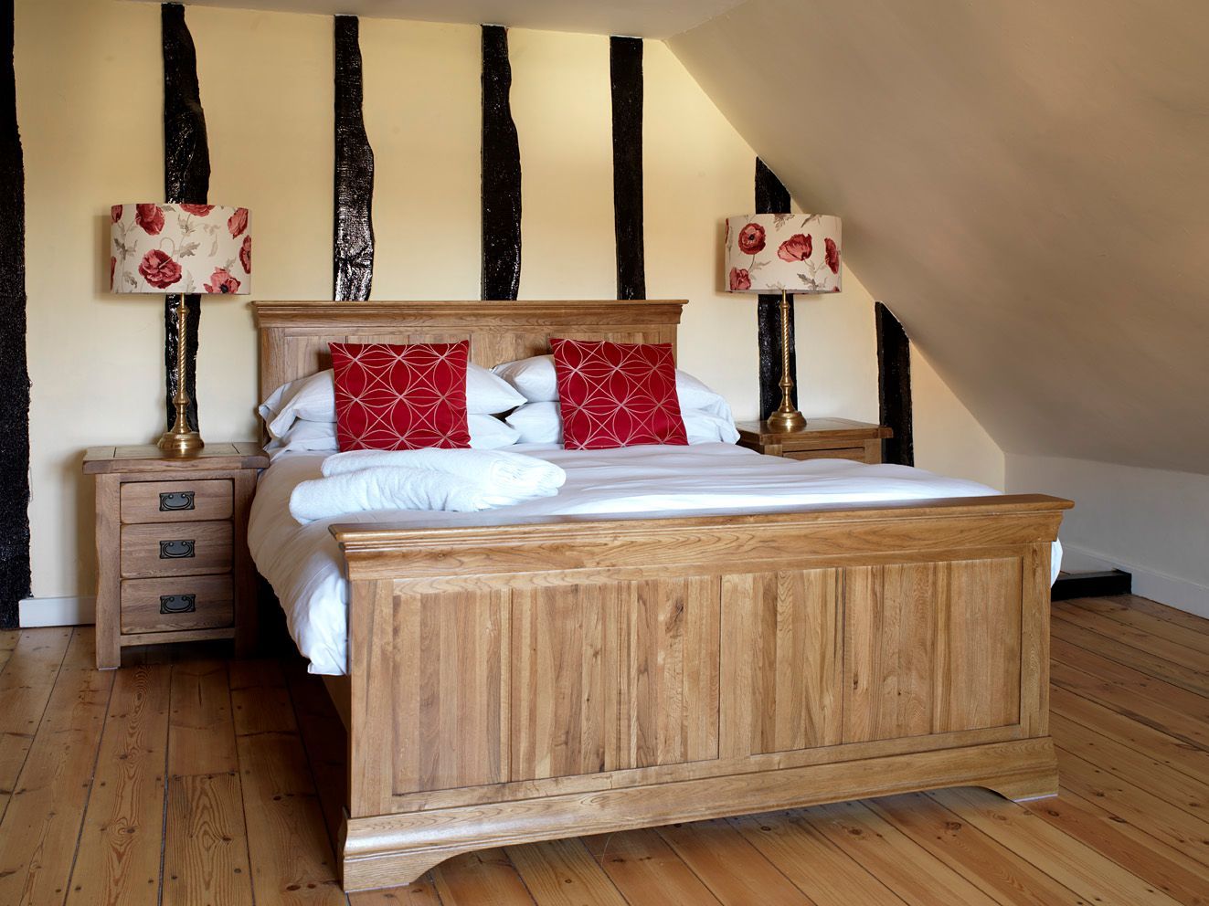Rustic bedroom with a wooden bed, red patterned pillows, and striped wall beams