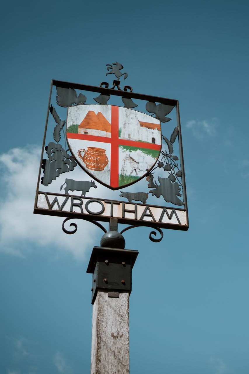 Decorative Wrotham village sign on a post against a blue sky