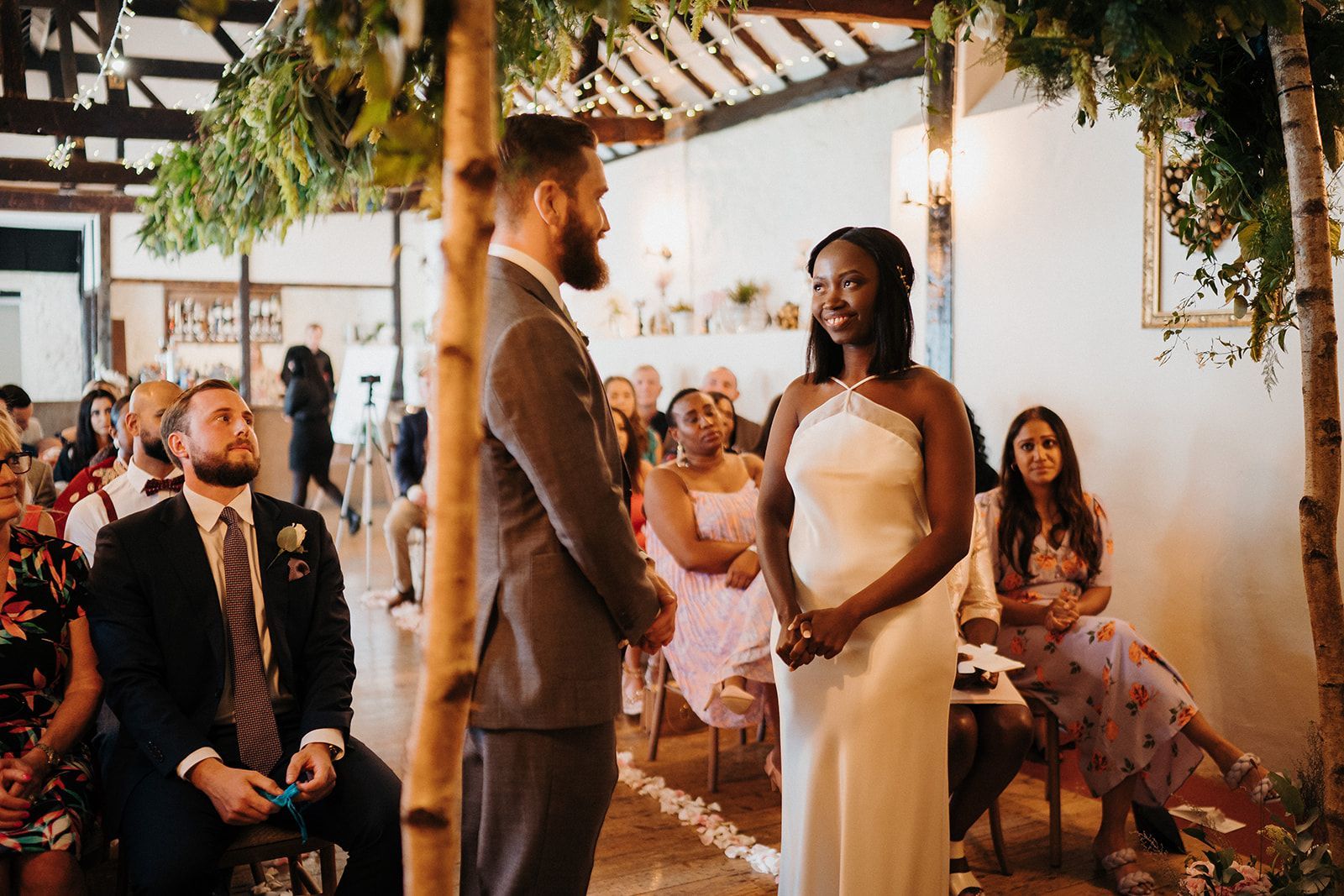 Couple exchanging vows at an outdoor wedding ceremony under a decorated pergola