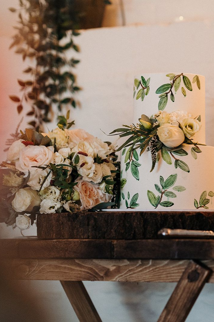 Three people holding bouquets of white roses with greenery at a formal event
