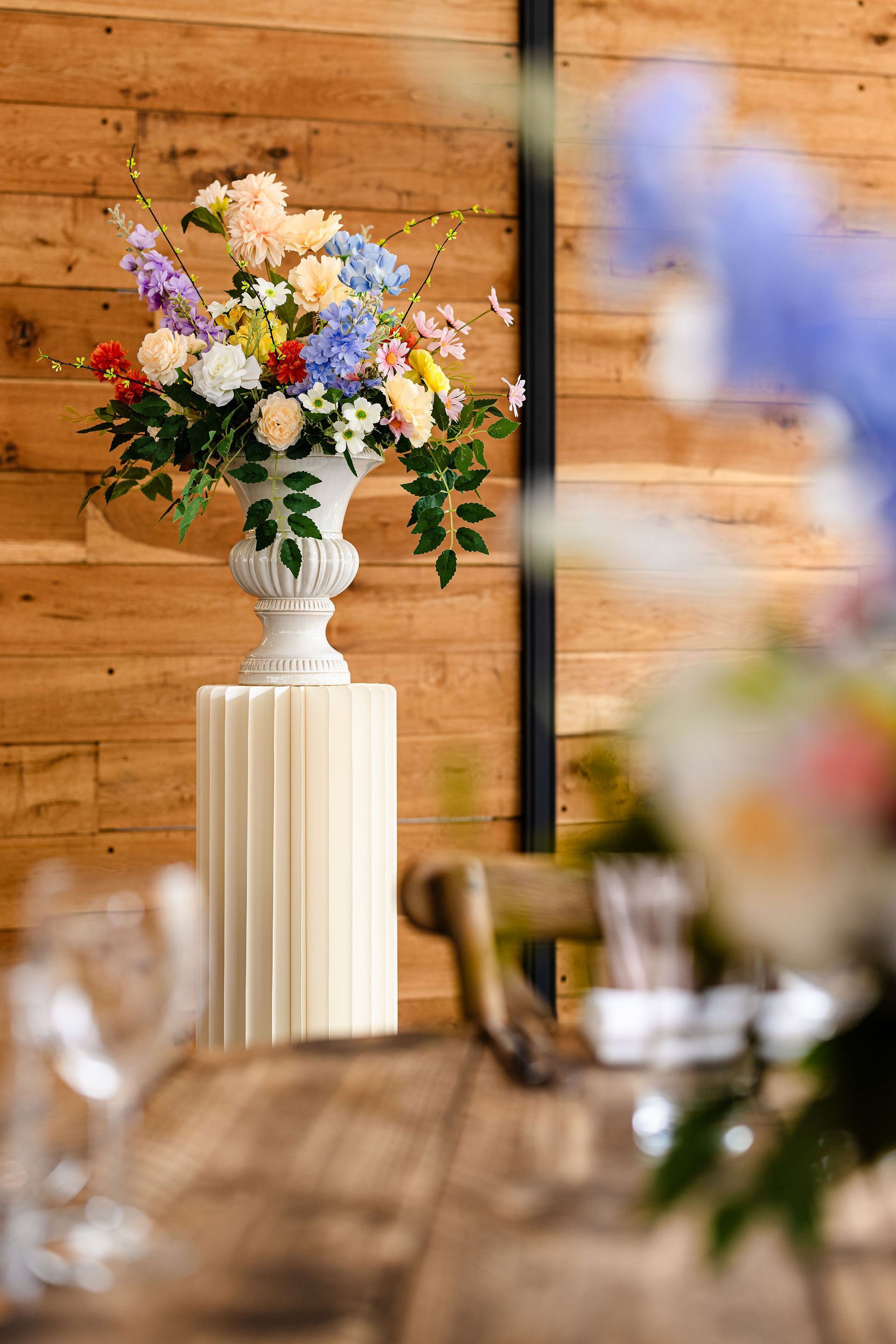 Tabletop wedding display with framed photos, cards, and a gold-framed sign at a rustic wooden venue
