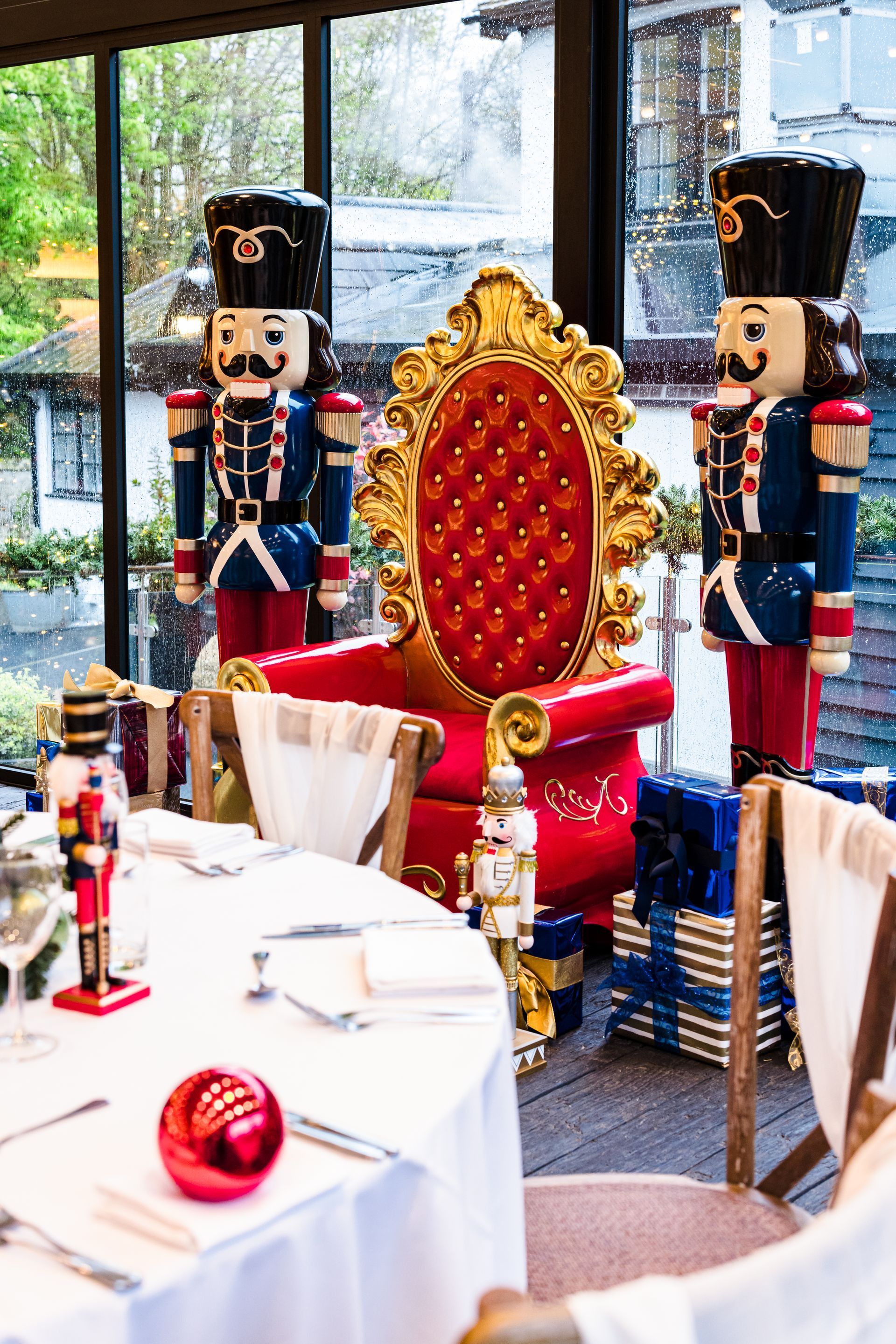 Decorative holiday table setting with a red-and-gold throne and toy soldiers by large windows