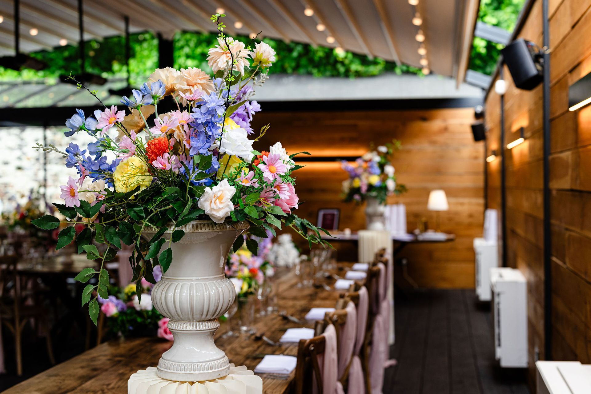 Elegant banquet hall with white table settings, floral centerpieces, and warm wood walls