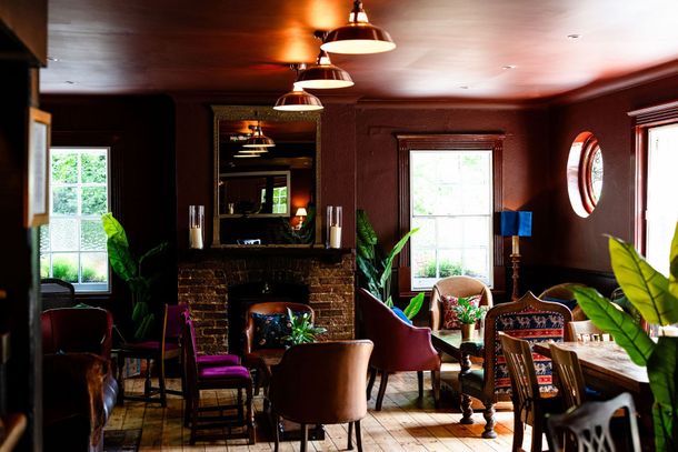 Two people smiling and talking on a leather couch in a cozy café, with drinks on the table.