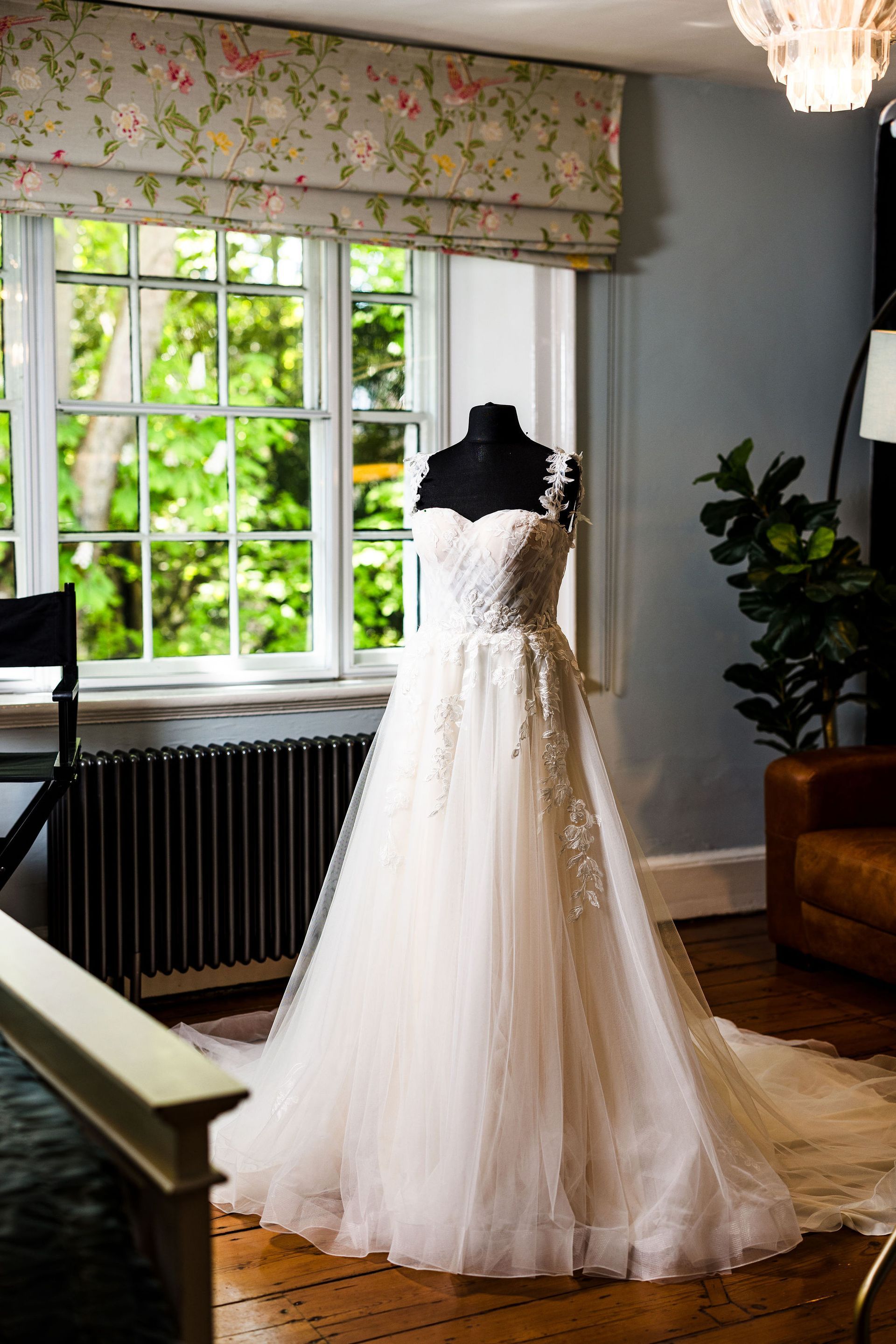 White lace wedding dress on a mannequin in a bright room by a window