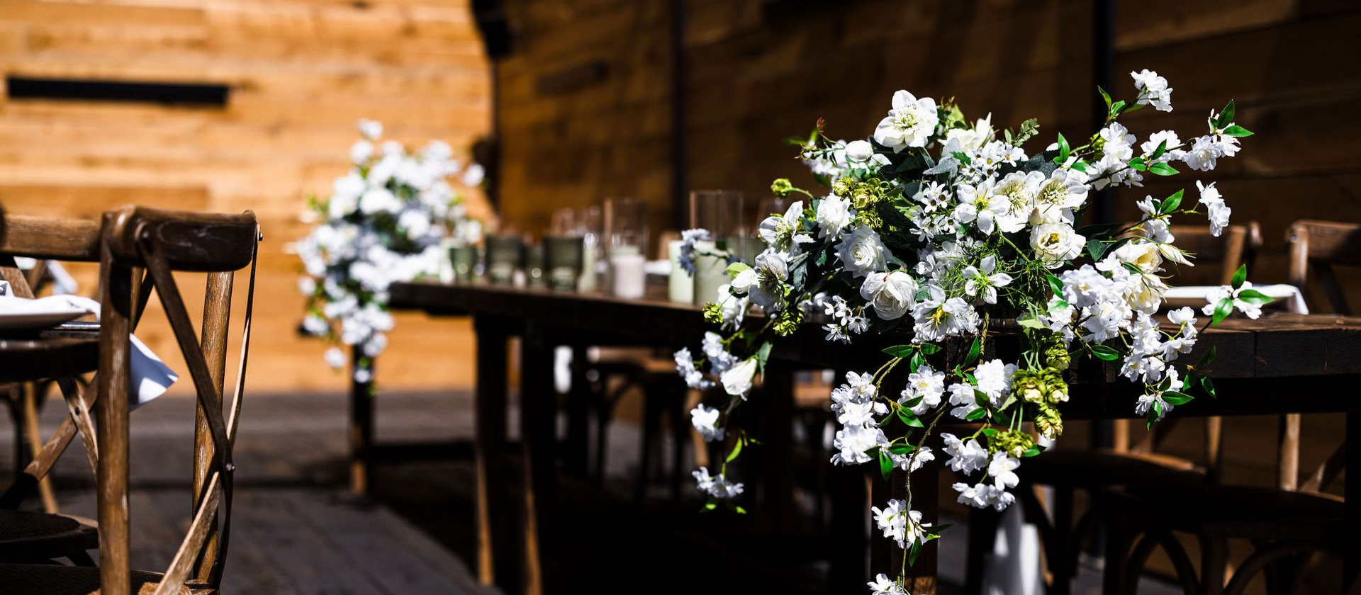 Rustic indoor event table with white and green floral centerpieces and warm wooden decor