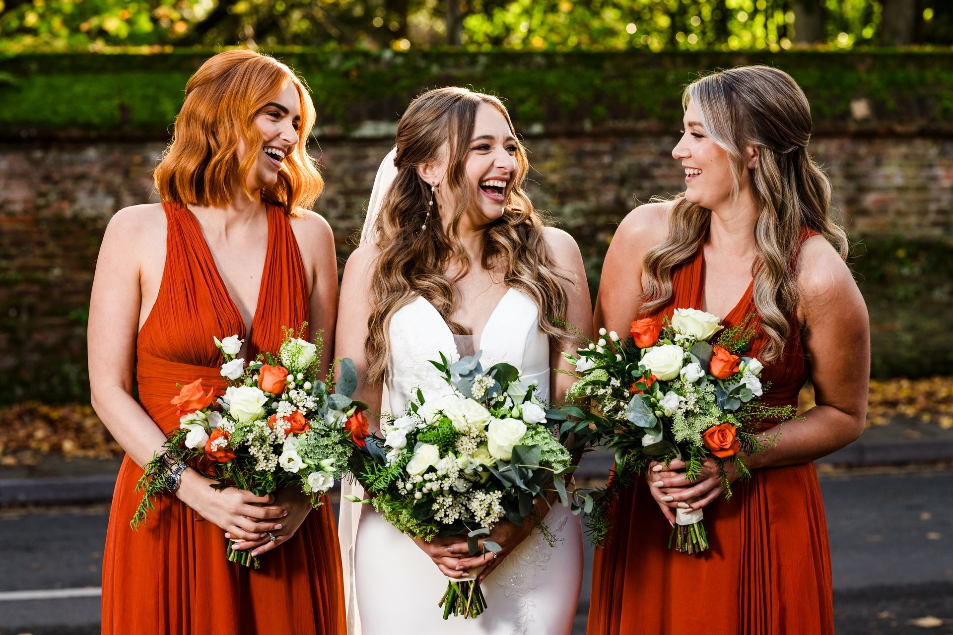 Bride in a white wedding dress being helped with her hair by a stylist in a red dress