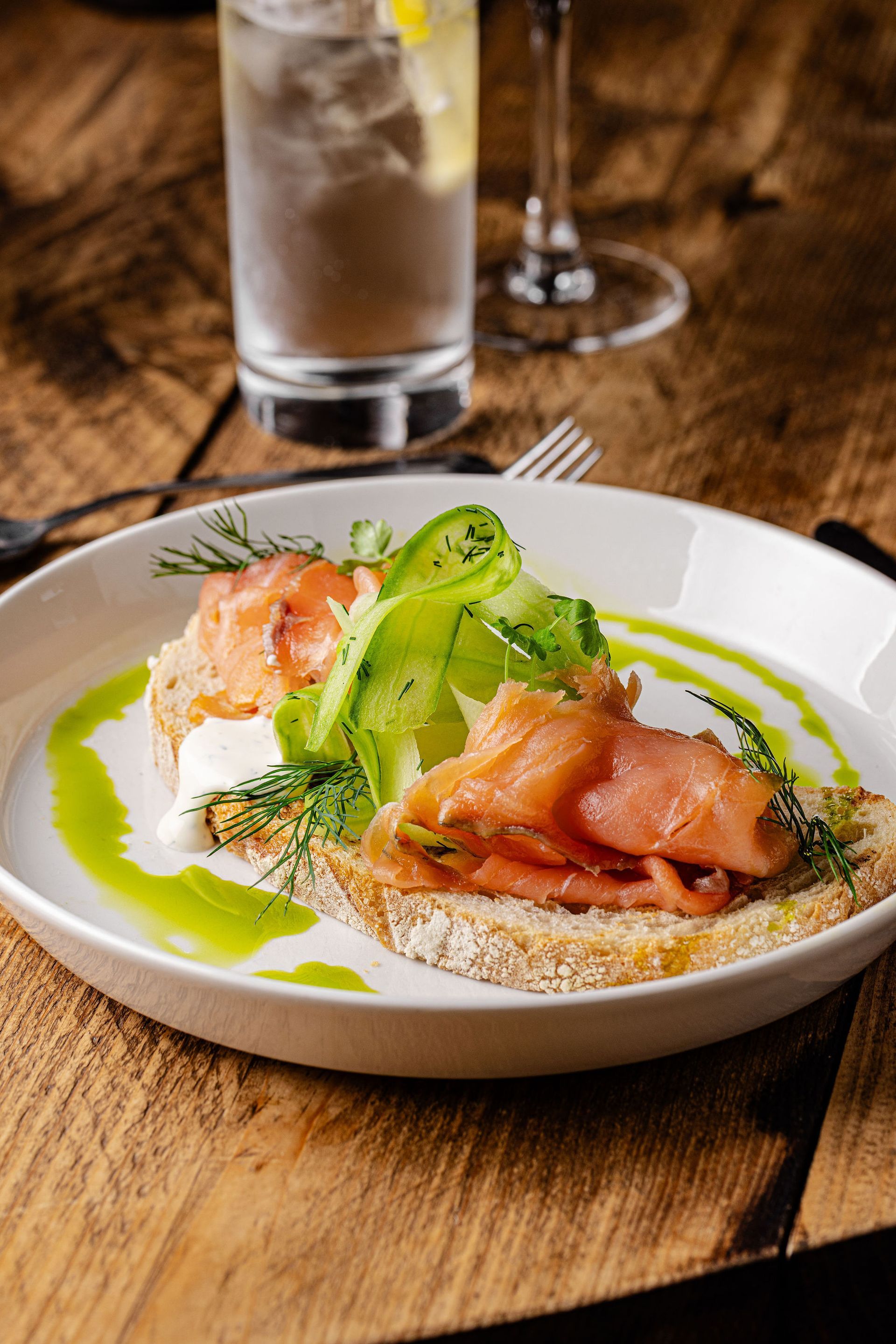 Overhead view of a plated salad on a rustic table with cutlery and drinks nearby