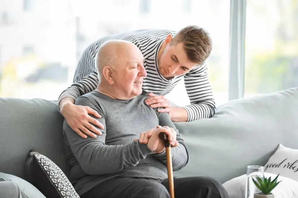 A Younger Person With a Striped Shirt Leans Over a Couch — CQ Home Care in Yeppoon, QLD