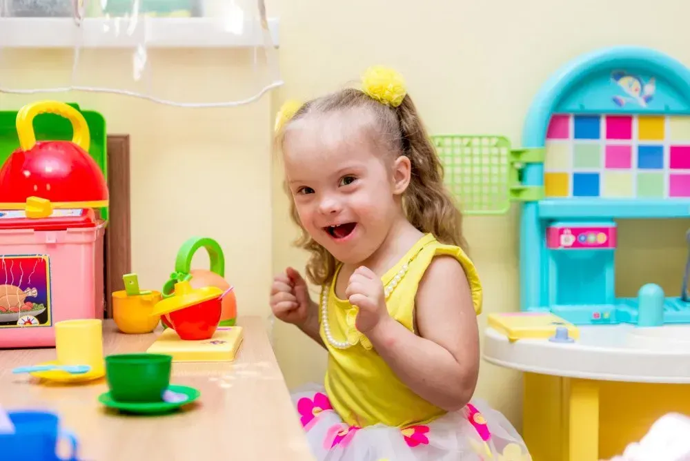 Smiling Child With Blonde Hair in Pigtails Plays With Colorful Toy — CQ Home Care in Yeppoon, QLD