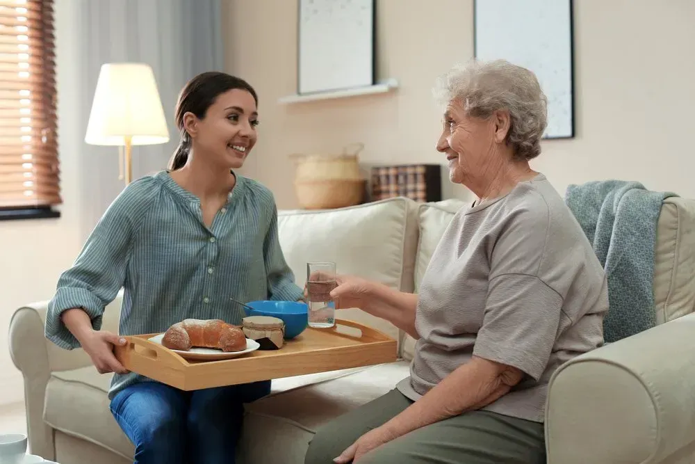 Caregiver Smiling as She Serves a Tray — CQ Home Care in Yeppoon, QLD