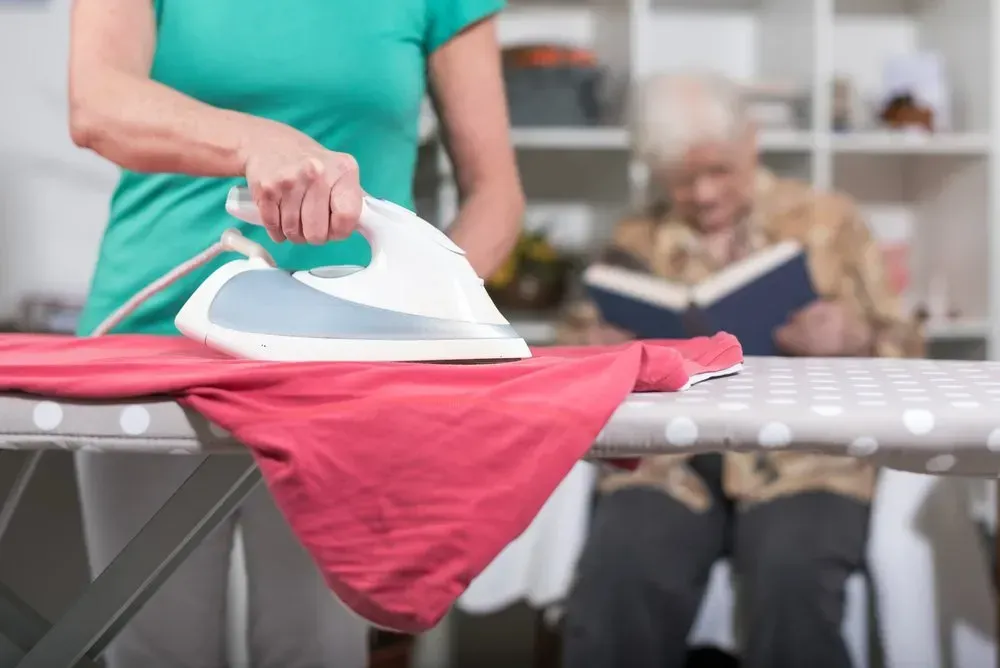 Person Irons a Pink Garment on a Polka-dot Board — CQ Home Care in Yeppoon, QLD