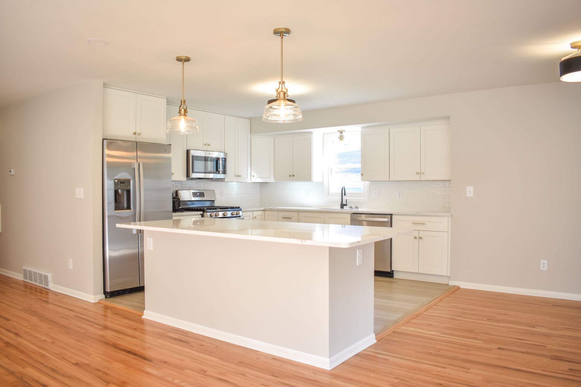 Kitchen with wooden cabinets, white appliances, coral wall, and tiled backsplash.