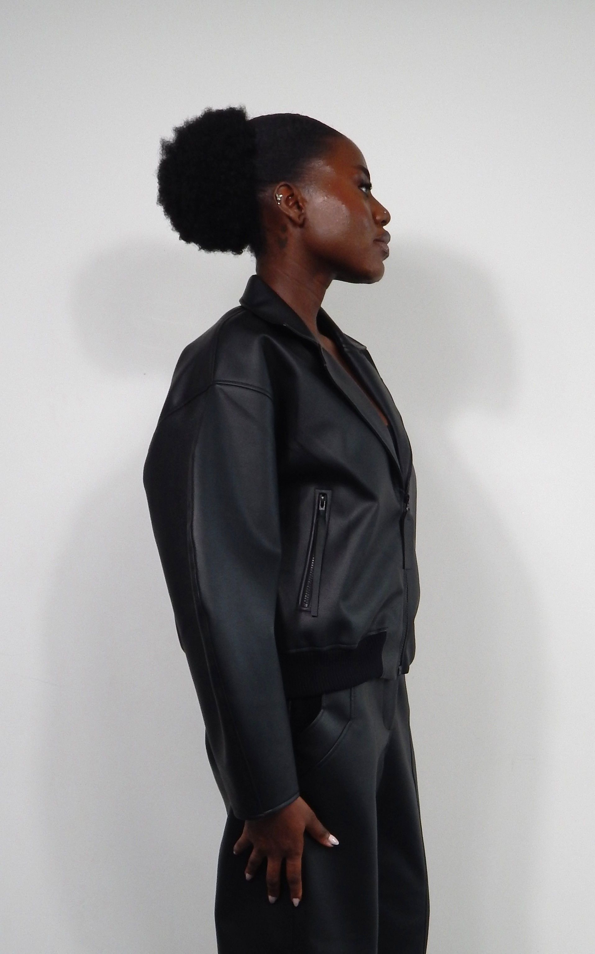 Woman in black leather jacket and pants, looking up.