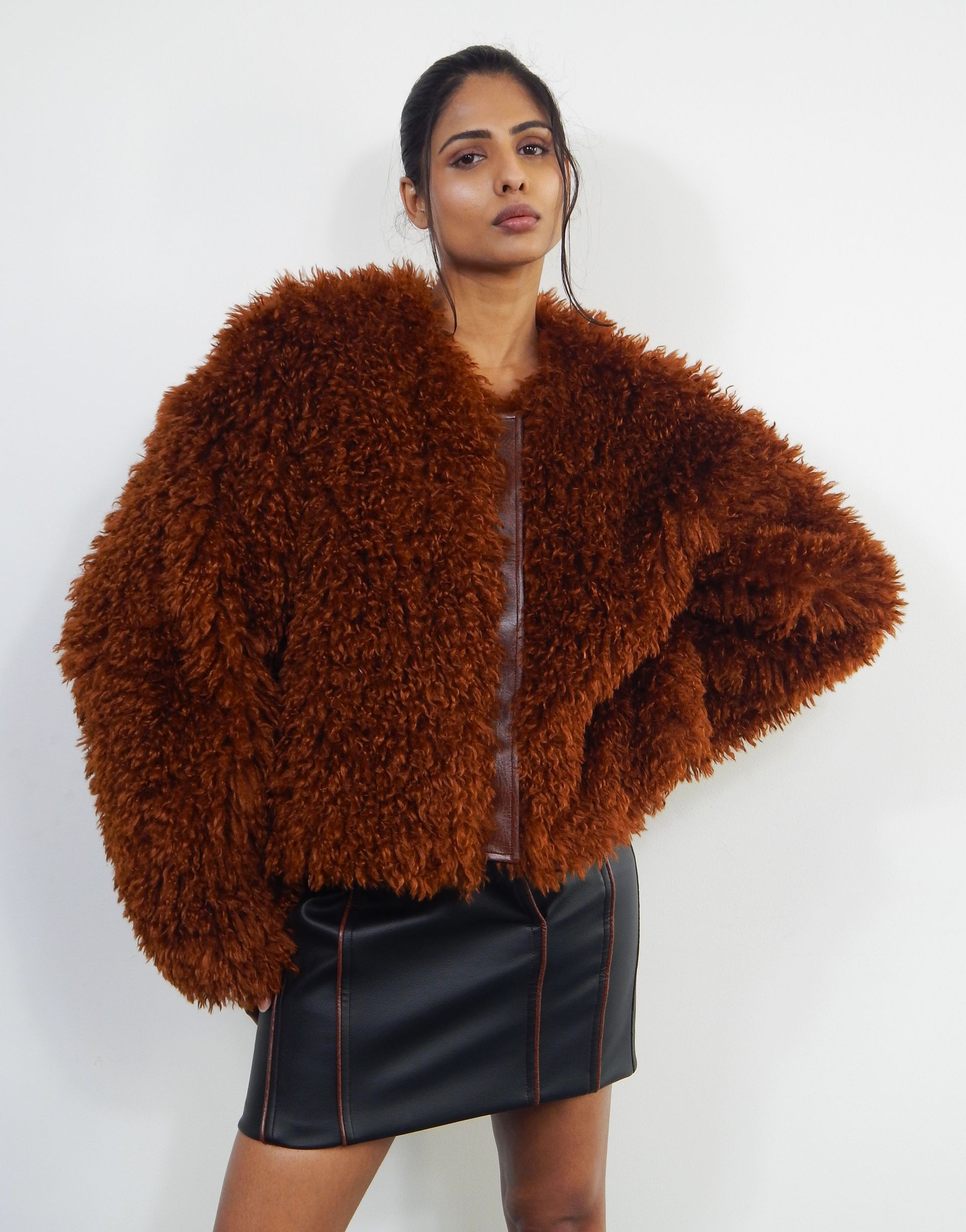 Woman wearing brown furry jacket, black skirt.