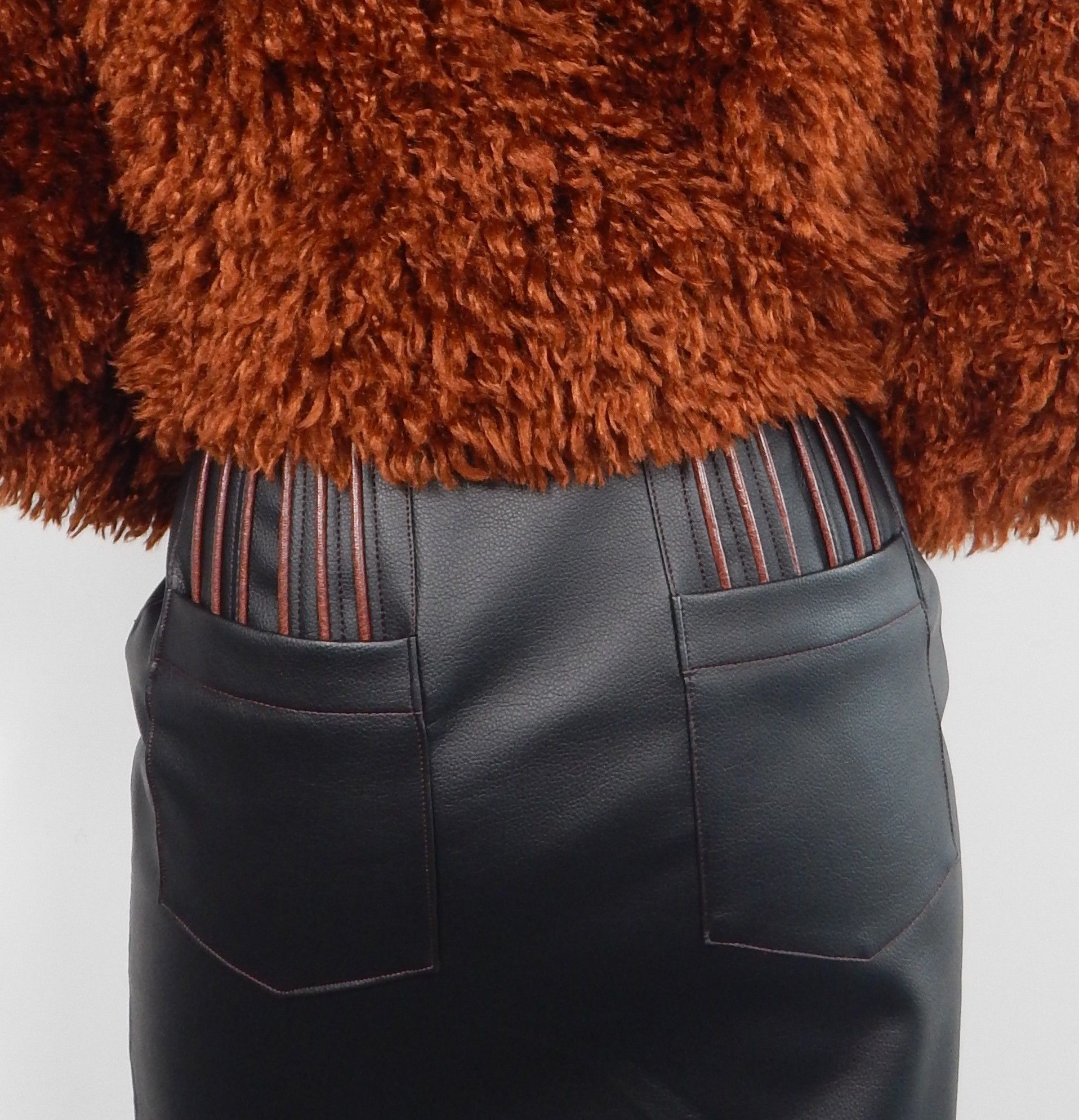 Cropped view of person in a fuzzy brown jacket and black skirt. The skirt has visible stitching.