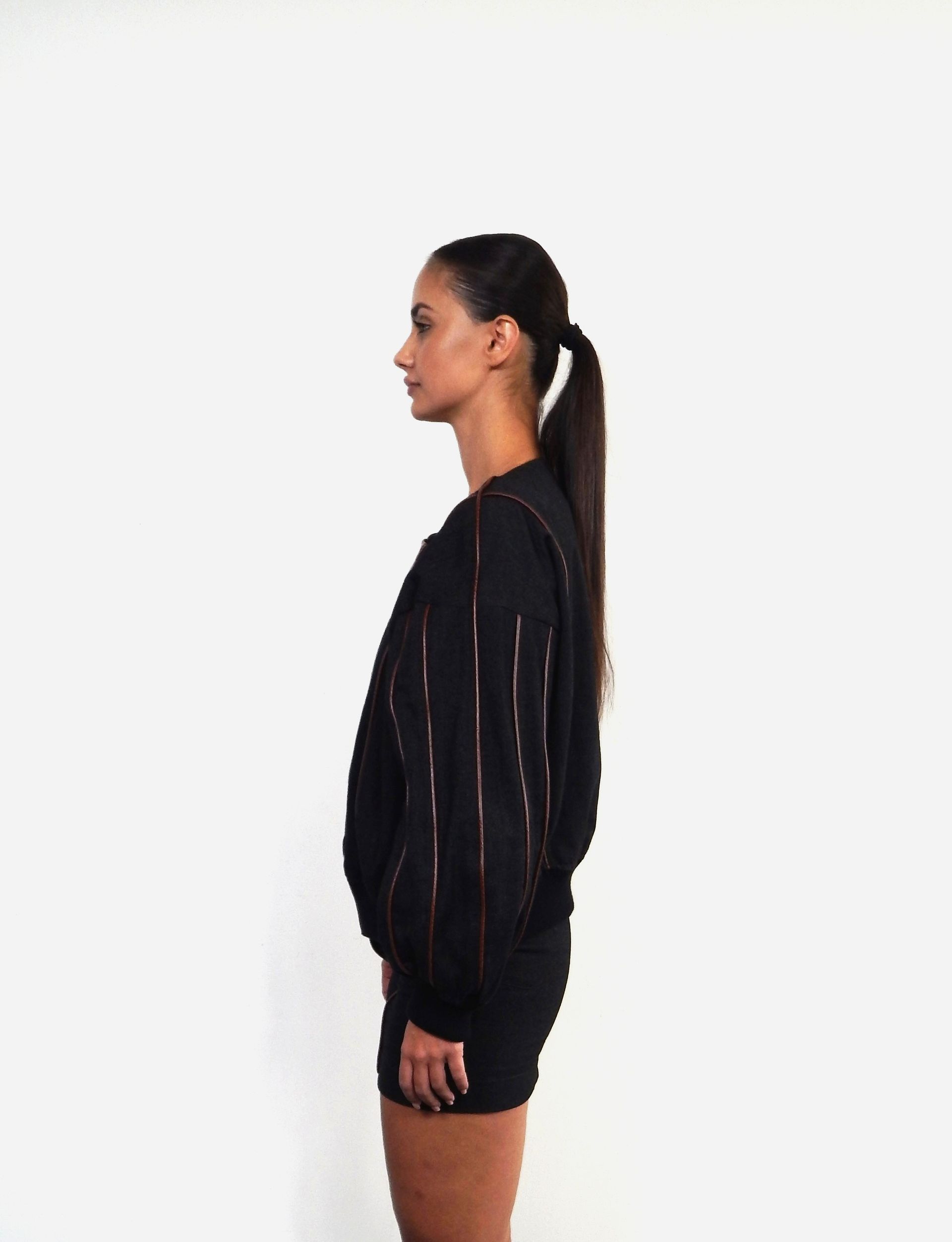 Woman wearing a black and brown textured sweatshirt and skirt, standing against a white backdrop.