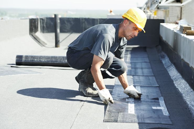A man wearing a hard hat is working on a roof.