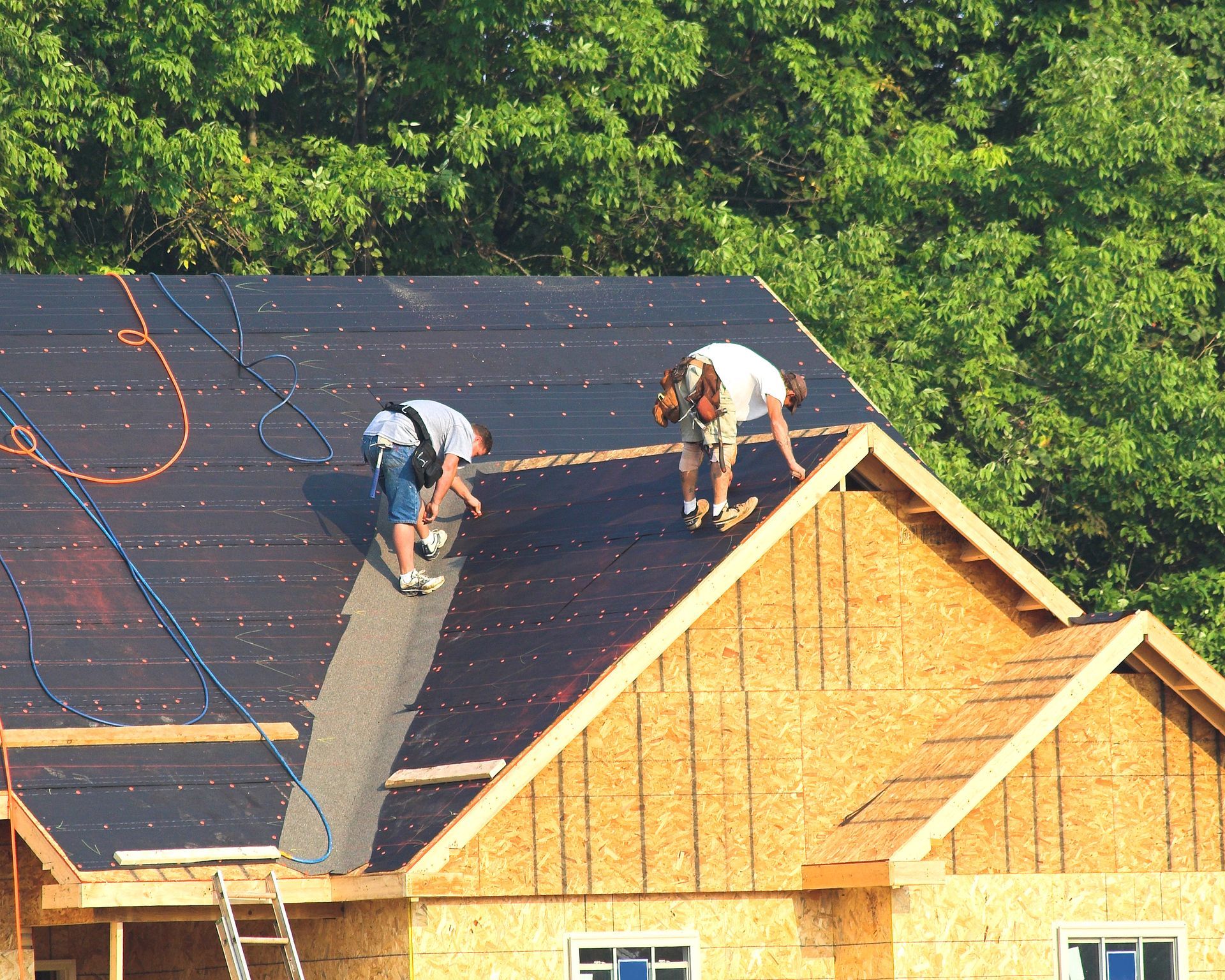 Two men are working on the roof of a house under construction