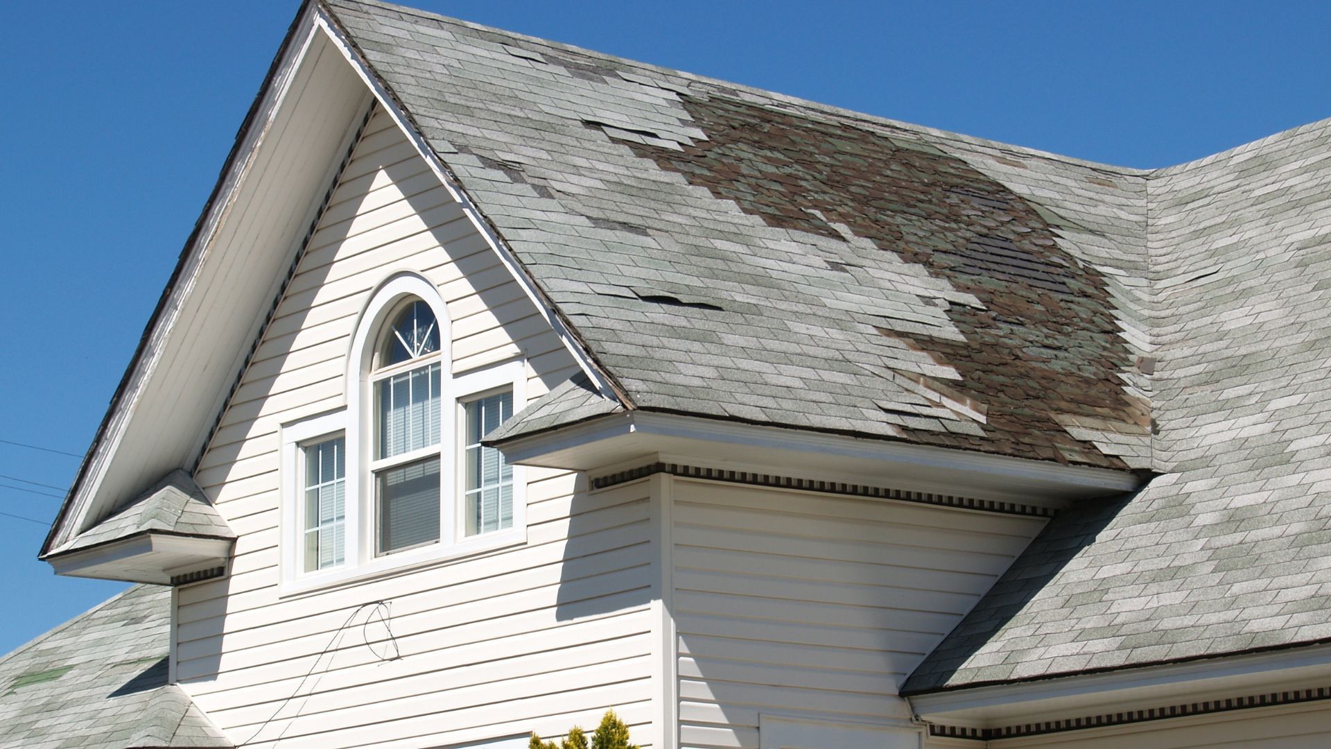 A white house with a roof that is missing shingles