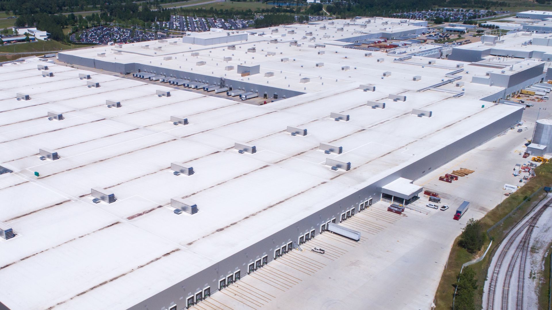 An aerial view of a large warehouse with a white roof.