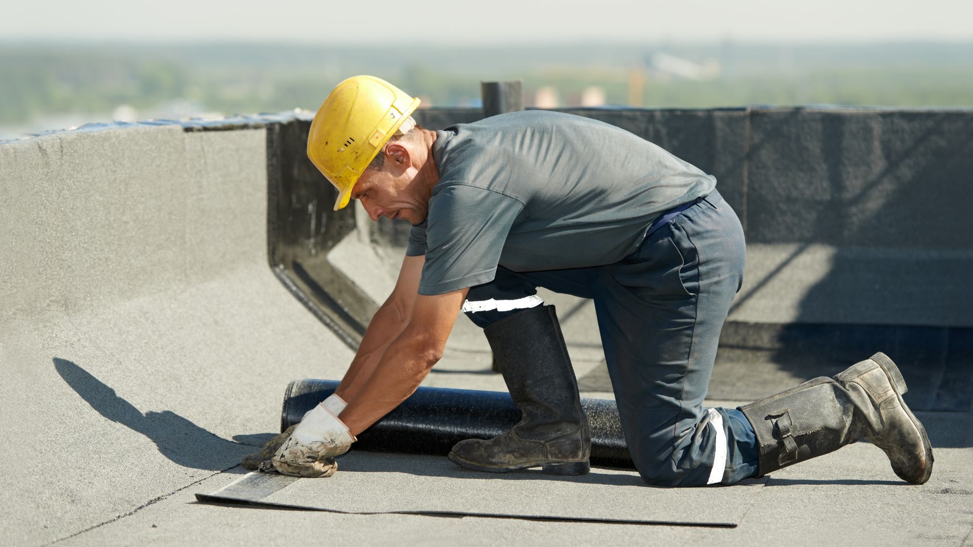 A man wearing a hard hat is working on a roof.